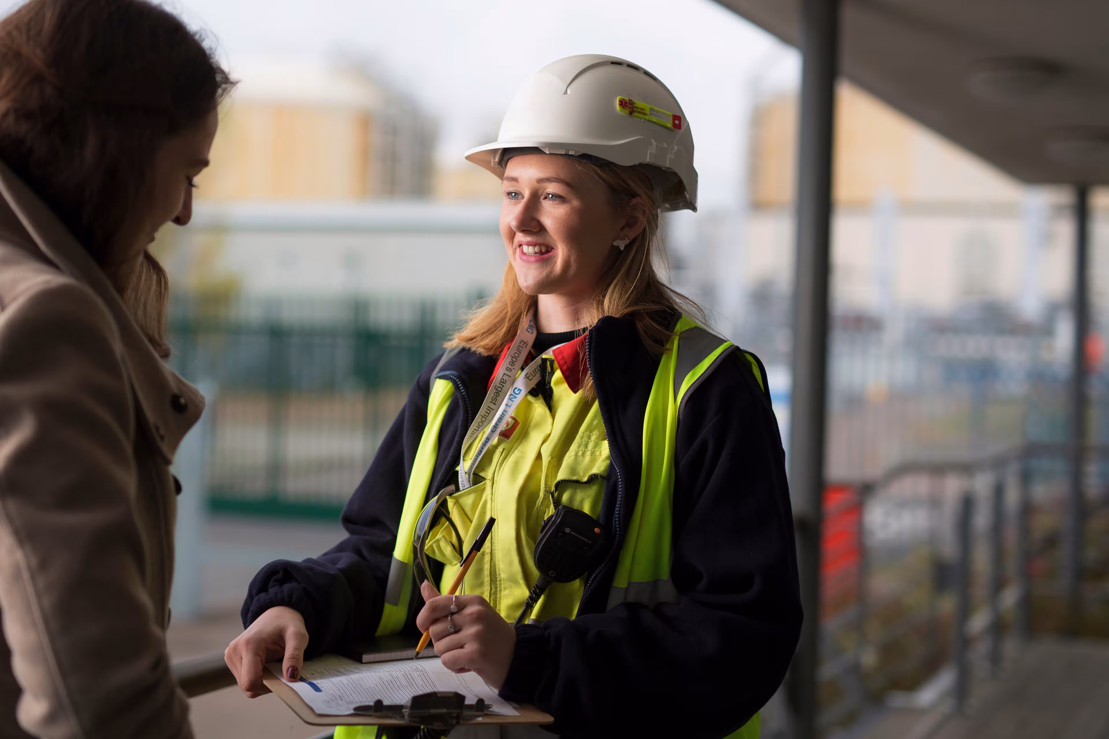 Construction worker in hard hat and safety vest discussing plans with colleague at job site